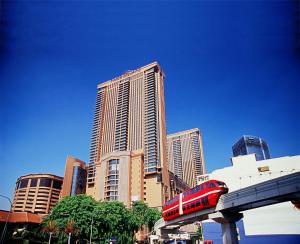 a red train on a bridge in front of tall buildings at Sunbow Suites @ Times Square Kuala Lumpur in Kuala Lumpur