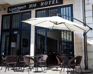 a table with chairs and an umbrella in front of a hotel at Hotel N16 in Batumi