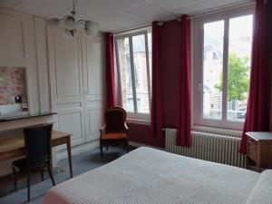 een slaapkamer met een bed, een bureau en 2 ramen bij Hotel Victor Hugo in Amiens