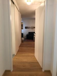 pasillo que conduce a una sala de estar con paredes blancas y suelo de madera. en Premarental Apartment 1, en Viena