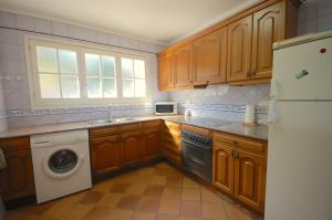 a kitchen with wooden cabinets and a washer and dryer at Lets Holidays Sailor House with Sea Views in Tossa de Mar