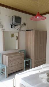 a bedroom with a dresser and a tv on the wall at Studios Ntina in Alyki