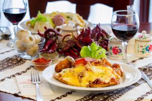 una mesa con un plato de comida y copas de vino en Hotel Rózsa Csárda Bungalow & Caravan Park en Hegyeshalom