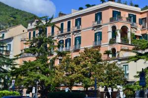 un bâtiment rose avec des arbres devant lui dans l'établissement La Maison du Paradis, à Salerne