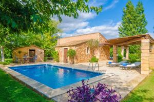 a swimming pool in a yard with a stone house at Ses Tendes in Algaida