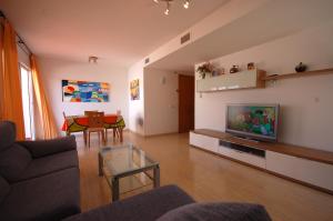 a living room with a couch and a tv and a table at Lets Holidays Big Terrace House and 2 Parking in Tossa de Mar