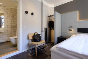 a bedroom with a bed and a chair and a bathroom at Zleep Hotel Copenhagen City in Copenhagen