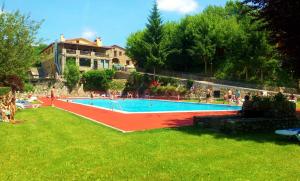a large swimming pool with people in a yard at Hostal Els Roures in Camprodon