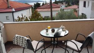 a table and chairs on a balcony with a laptop at Sobe Tonica in Krk
