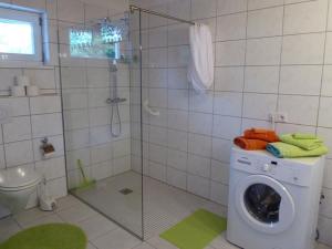 uma máquina de lavar roupa na casa de banho com um chuveiro em Ferienhaus Geißdörfer em Hunding