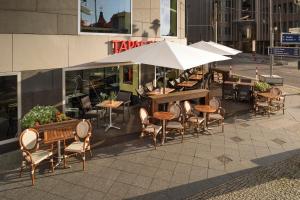 eine Terrasse mit Tischen, Stühlen und einem Sonnenschirm in der Unterkunft Meliá Berlin in Berlin