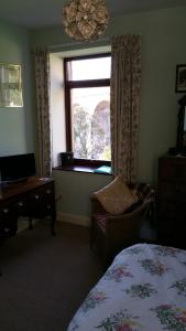 a bedroom with a bed and a desk and a window at Castle Vale House in Berwick-Upon-Tweed