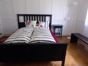 ein Bett mit einem schwarzen Rahmen und Kissen darauf in der Unterkunft Chalet in Bern in Bern