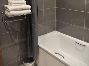 Raglan Lodge في مونموث: حمام مع حوض استحمام أبيض ومناشف