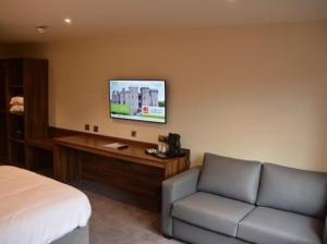 a bedroom with a bed and a couch and a tv at Raglan Lodge in Monmouth