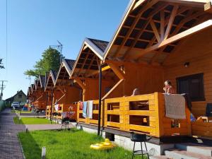 a row of wooden buildings with people sitting in them at U Sasiadow in Mielenko