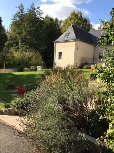 a garden with a white building with a black roof at Gite Nature Loire et Châteaux 3* in Villandry