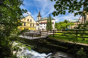 a castle with a river in front of it at Yellow Ski Apartments in Rokytnice nad Jizerou