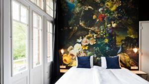 a bedroom with a painting of flowers on the wall at Rijksmonument Hotel de Sprenck in Middelburg