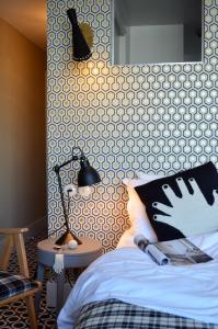 ein Schlafzimmer mit einem Bett und einem Tisch mit einer Lampe in der Unterkunft Hotel Les Pilotes in Saint-Valery-sur-Somme