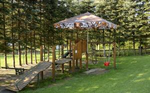 a playground with a swing set with an umbrella at Penzión Lesnica in Spišské Tomášovce