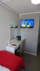 Zimmer mit einem Schreibtisch und einem TV an der Wand in der Unterkunft Drive-in Motell in Mjölby