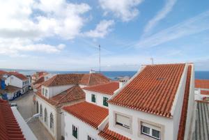 una vista de los tejados de los edificios y del océano en Casas do Norte, en Ericeira