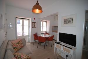 Una sala de estar con un sofá, un televisor y una mesa. en Casas do Norte, en Ericeira