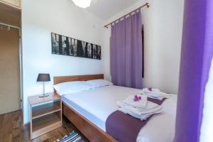 - une chambre avec un lit et un rideau pourpre dans l'établissement Apartment A&T Countryside, à Čilipi