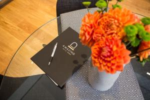 a table with a vase with orange flowers and a card at Amazing Piazza Venezia Suites in Rome