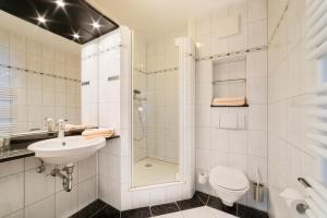 a bathroom with a shower and a sink and a toilet at Hotel Seeblick in Bernried