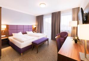 a hotel room with a king sized bed and a desk at Hotel Seeblick in Bernried