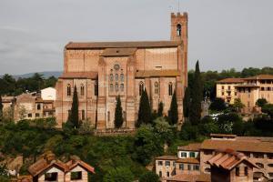 a large brick building with a tower in a town at Casa Vezzosa in Siena