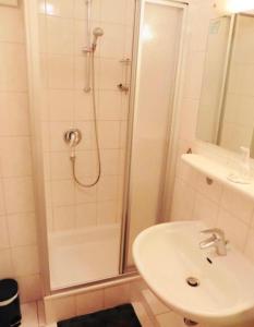 a white bathroom with a shower and a sink at Haus Windrose in Norderney