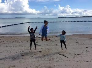 three children playing on the beach near the water at Pension Snadun in Ginoza