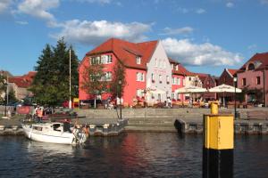 a boat in the water in front of a red building at Der Insulaner - Hotel & Restaurant in Malchow