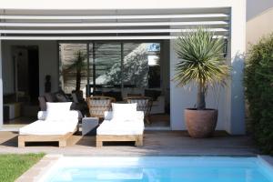 a pool in front of a house with white furniture at Casa da Ribeira in Aldeia do Meco