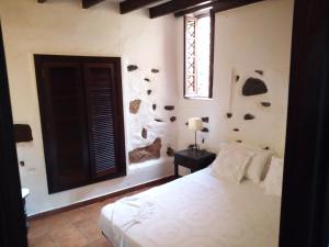 Casa Dos Barrancos في سانتا كروث دي تينيريفه: غرفة نوم بسرير ابيض ونافذة