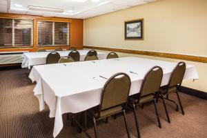 une salle de conférence avec des tables et des chaises blanches dans l'établissement AmericInn by Wyndham Menomonie, à Menomonie