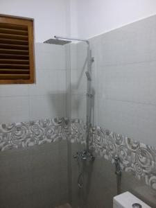 une douche avec une porte vitrée dans une salle de bain dans l'établissement Wick's Apartment, à Hikkaduwa