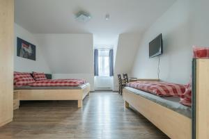 a room with two beds and a tv on the wall at Anitas Altstadtpension in Kelheim