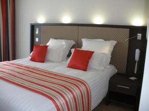 a bedroom with a large bed with red pillows at Hôtel Restaurant Splendid Camargue in Le Grau-du-Roi