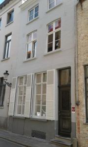a white house with white shuttered windows and a door at Guest house Adonis in Bruges