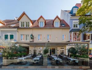 un edificio con tavoli e sedie di fronte ad esso di Pfeiler's Bürgerstüberl - Hotel a Feldbach