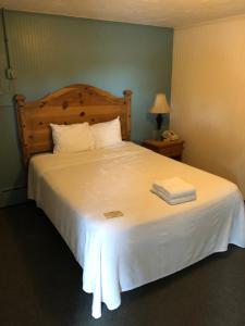 a bedroom with a large white bed with two towels on it at The Walpole Motel in Walpole