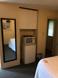 a room with a microwave and a bed and a mirror at The Walpole Motel in Walpole