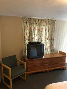 a room with a tv and a chair and a dresser at The Walpole Motel in Walpole