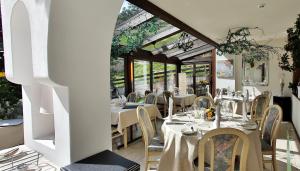 un restaurante con mesas y sillas blancas y ventanas en Residenz Larix Apartments en Davos