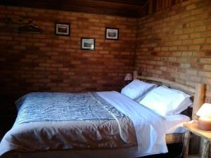 um quarto com uma cama com uma parede de tijolos em Pousada das Fadas em Visconde de Mauá