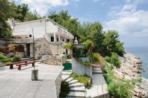 a house on the side of a cliff next to the ocean at Robinson Monte Cristo in Bogomolje